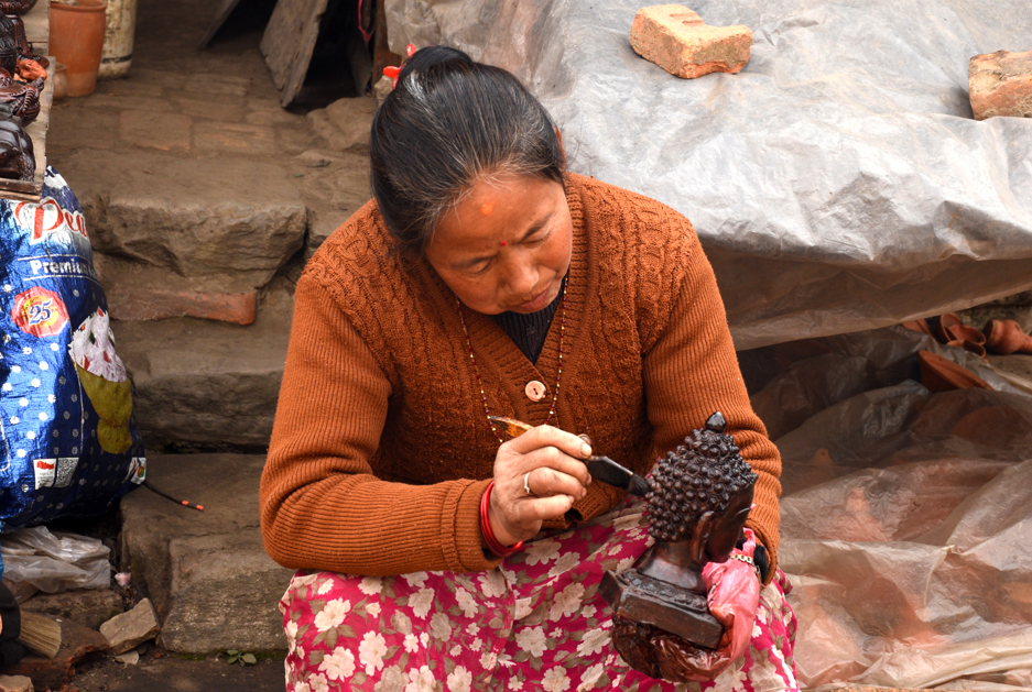 हस्तकला सामग्रीमा रङ्ग लगाउँदै महिला